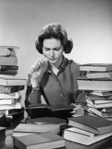 1950s-1960s-college-woman-studying-surrounded-all-around-by-piles-of-books